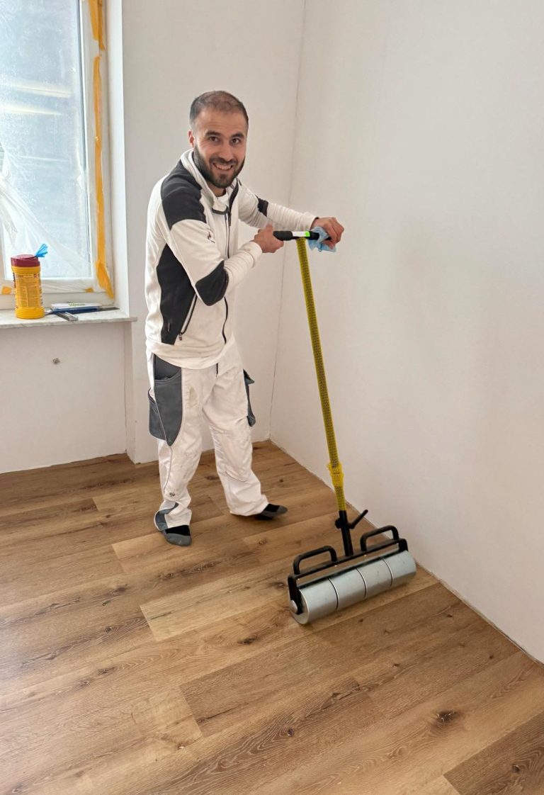 Designboden in einem Raum, teils verlegt, mit Bodenplanken im Hintergrund.